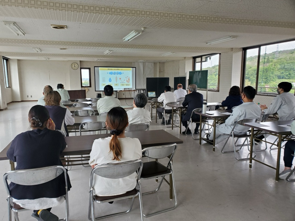 会議室でスクリーンを見ながら講習を受けている社員たちの様子