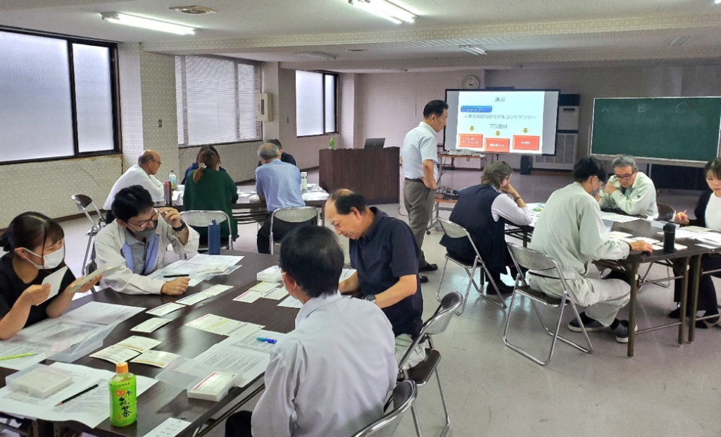 会議室でスクリーンを見ながら講習を受けている社員たちの様子