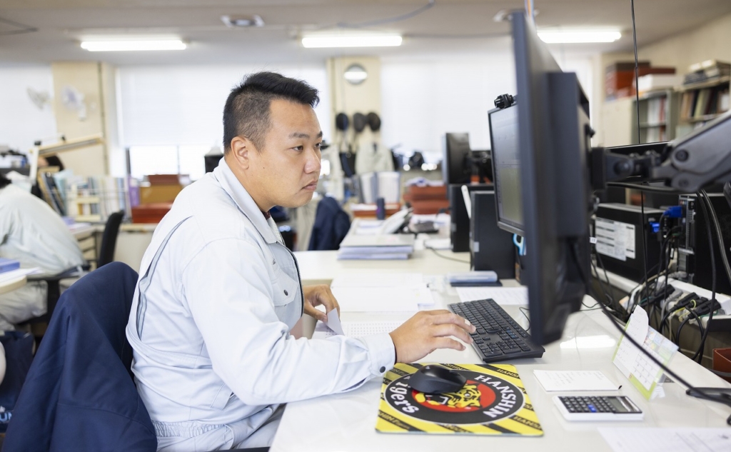 デスクでパソコンに向かい、業務を行っている男性社員