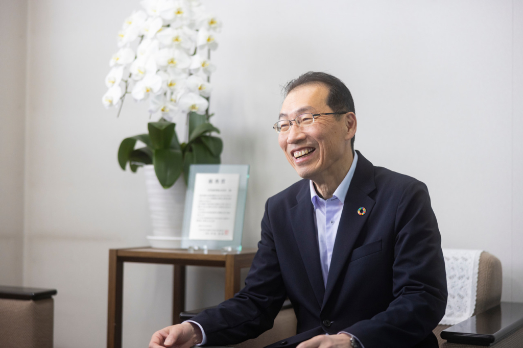 胡蝶蘭と表彰状の横に座る阿部社長