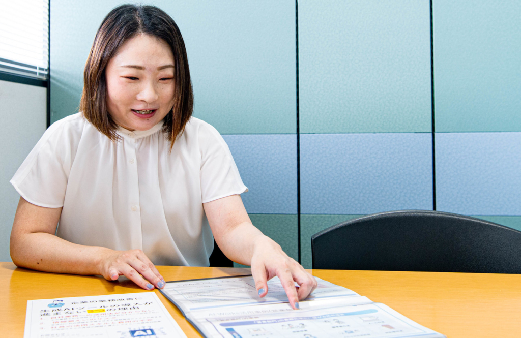 机の上に広げた資料を指差し、説明をしている岩野さん