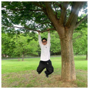 サングラスをかけて公園の木にぶら下がっている私服姿の小柳さん