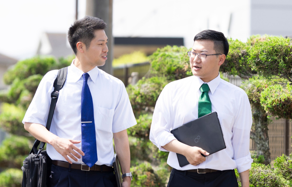 屋外の通りを、同僚の男性と並んで歩いている田口さん