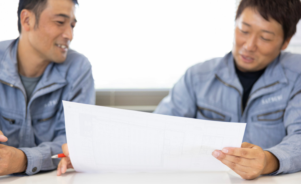 オフィスで同僚の男性と打ち合わせをしている明石さん