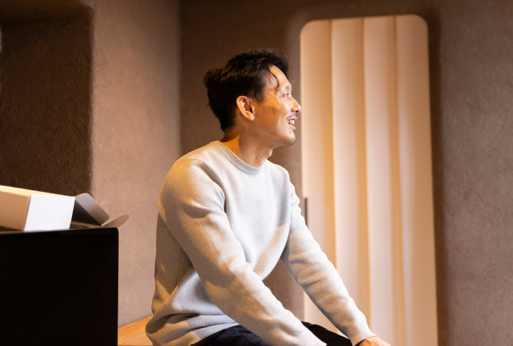 笑顔で横を向いて話を聞いている羽田さん