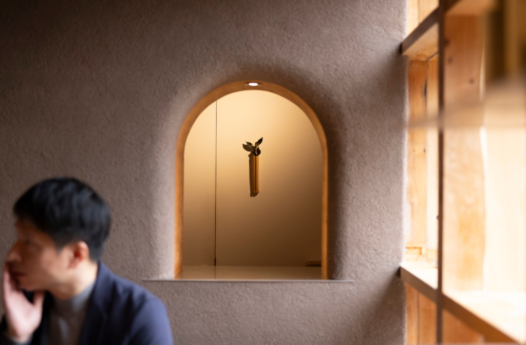 室内で頬に手を当てて話を聞いているインタビュアー