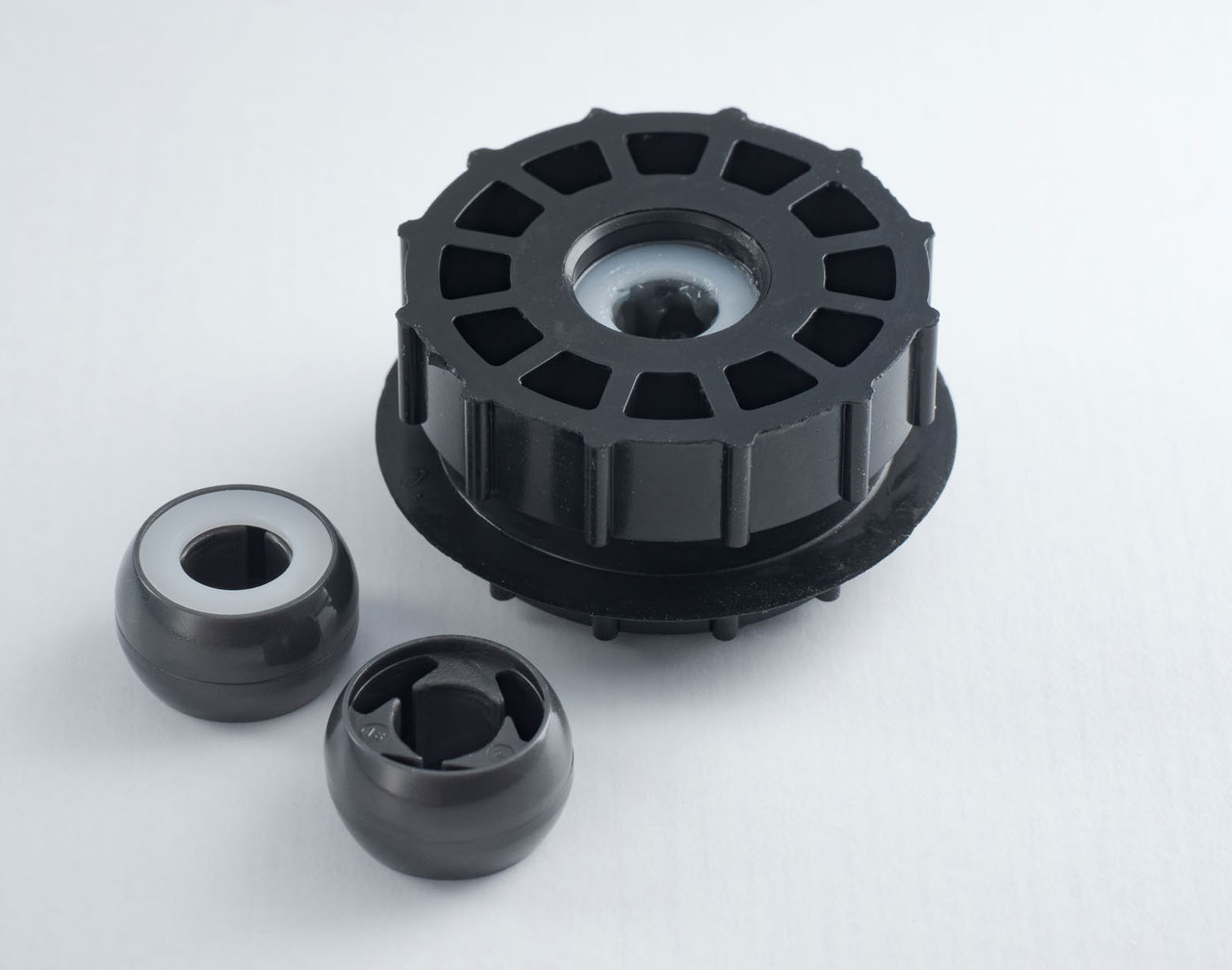 白い背景に置かれた、エアコンのモーター部分などに使われる黒色の精密プラスチック部品