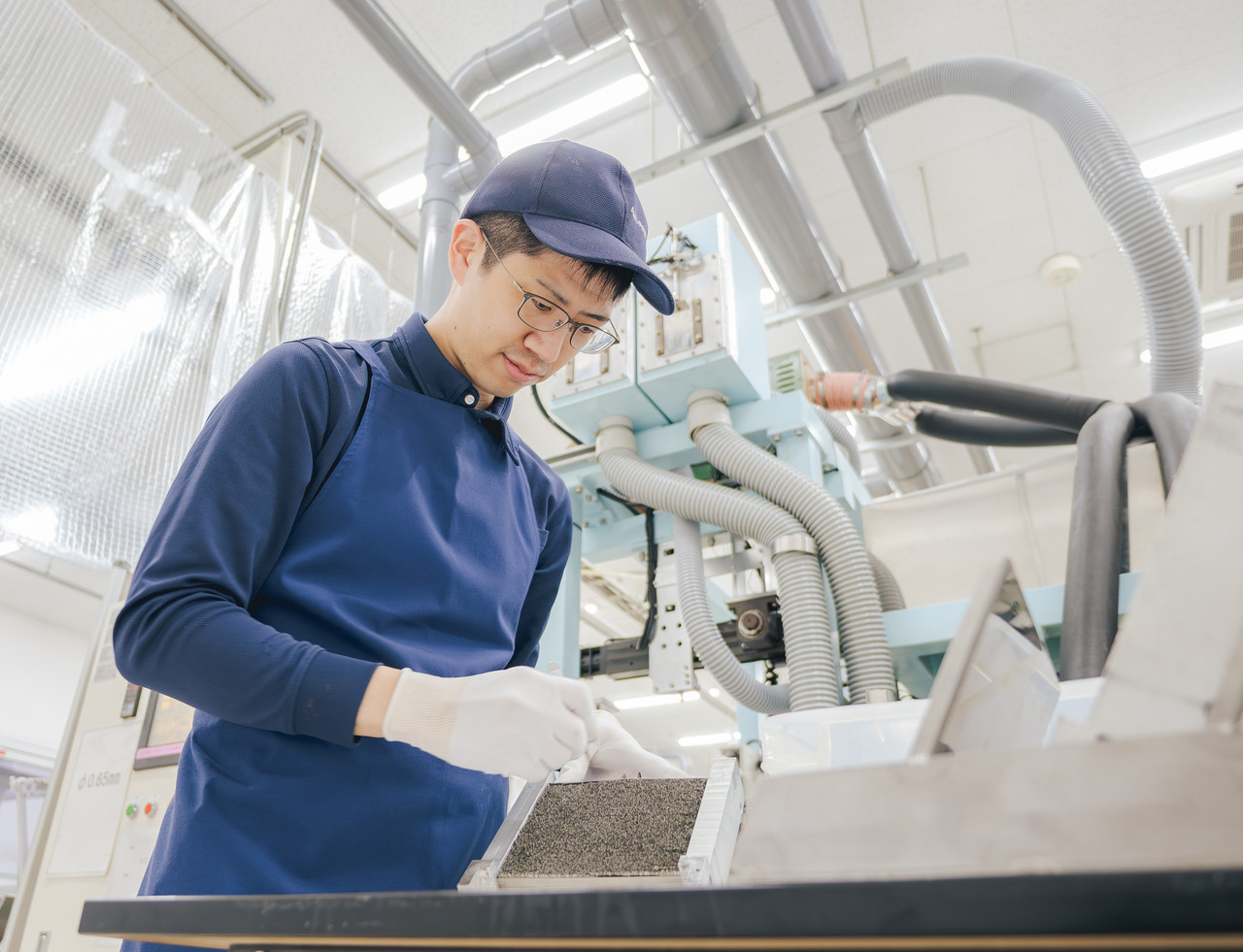 白い手袋をして、作業台に向かって仕事をしている森脇さん