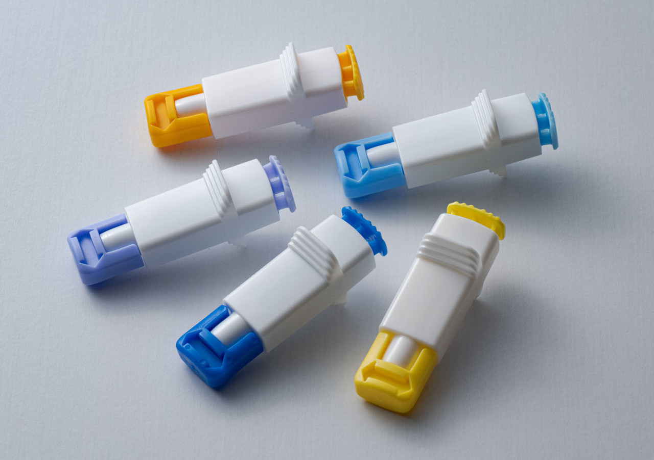 白い背景に置かれた、青、水色、黄色のキャップがついた5本の医療用採血器具ランセット