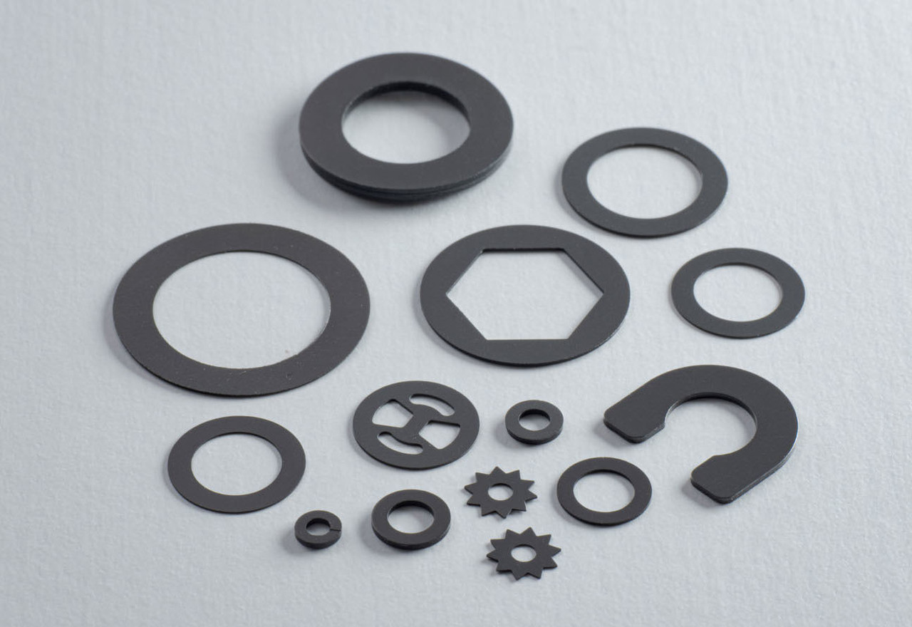白い背景に複数並べられた、様々なサイズと形状の黒いポリスライダーワッシャー
