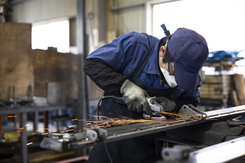 ディスクグラインダーを使って手作業で金属を研磨する作業員