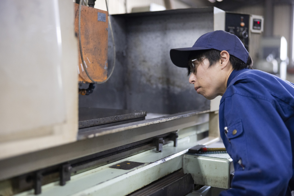 加工機の中を覗き込みながら作業をする男性社員
