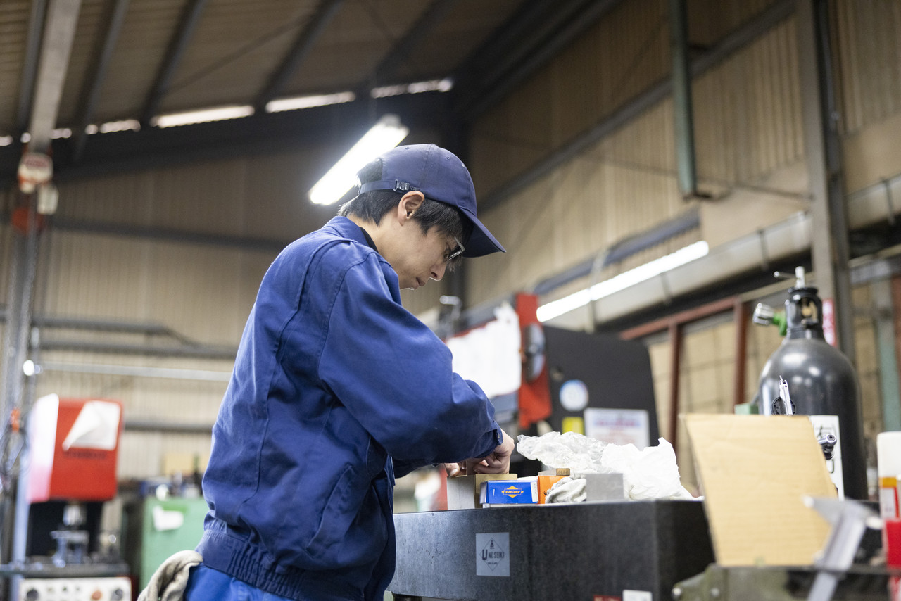 工場内の卓上で手作業を行う上鶴さん