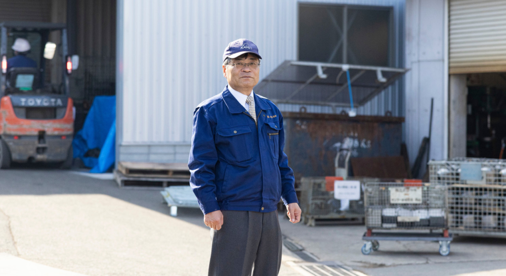 工場の前に立つ小虎修一さん
