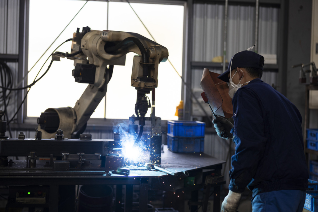 火花を散らしながら金属部品を溶接するロボットアーム