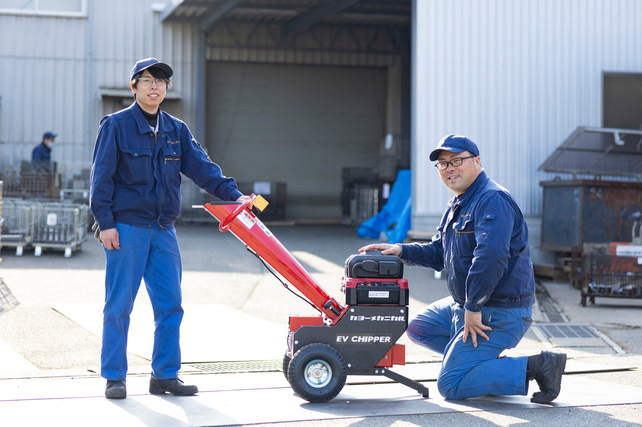 自社製品のEVウッドチッパーと並ぶ2名の男性社員