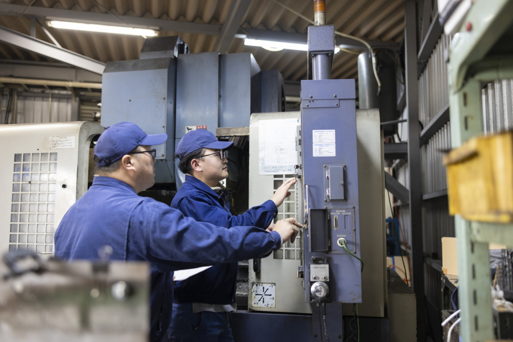 機械の操作パネルを見ながら会話をする2名の男性社員