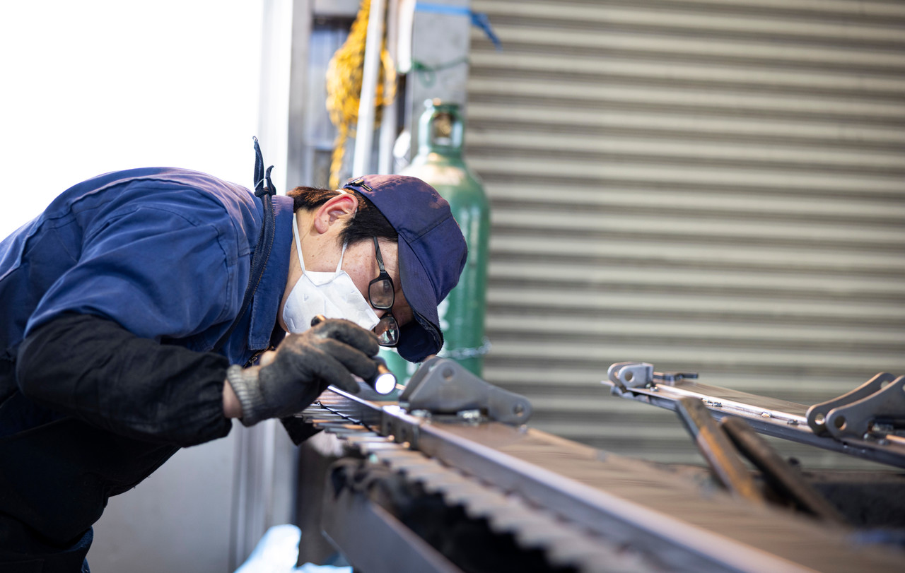 ライトを照らして部品を目視検査する藤田さん