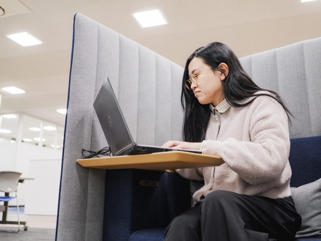 集中ブースでノートパソコンを使って作業する社員