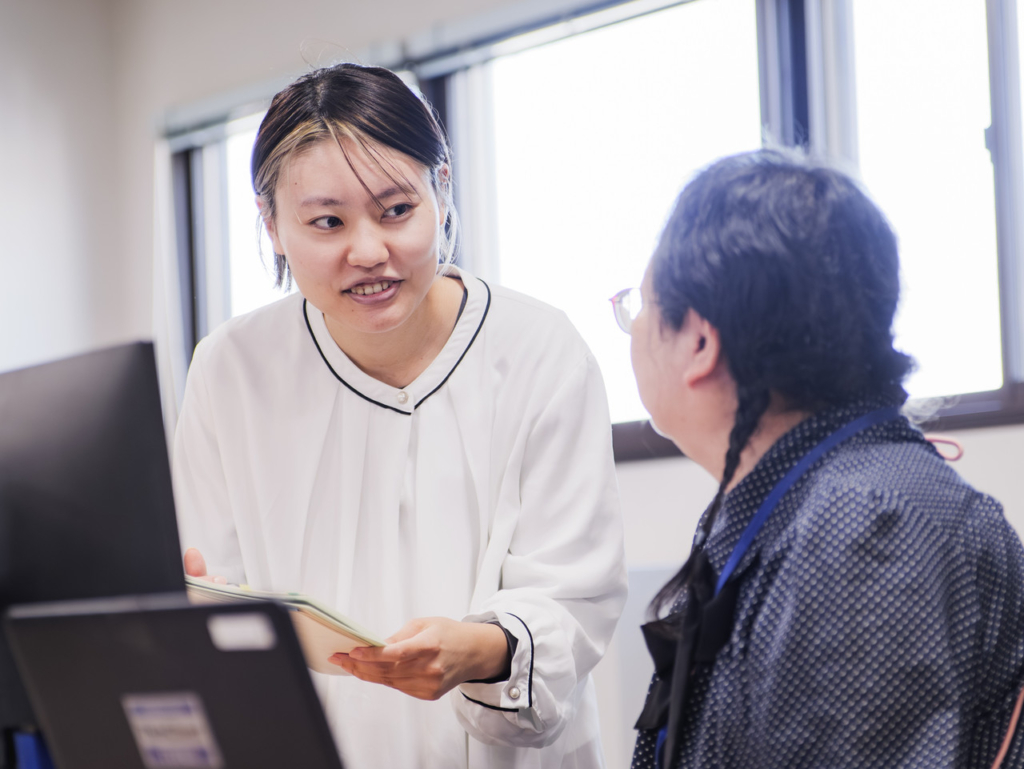 資料を持って立ち話をしている2名の社員