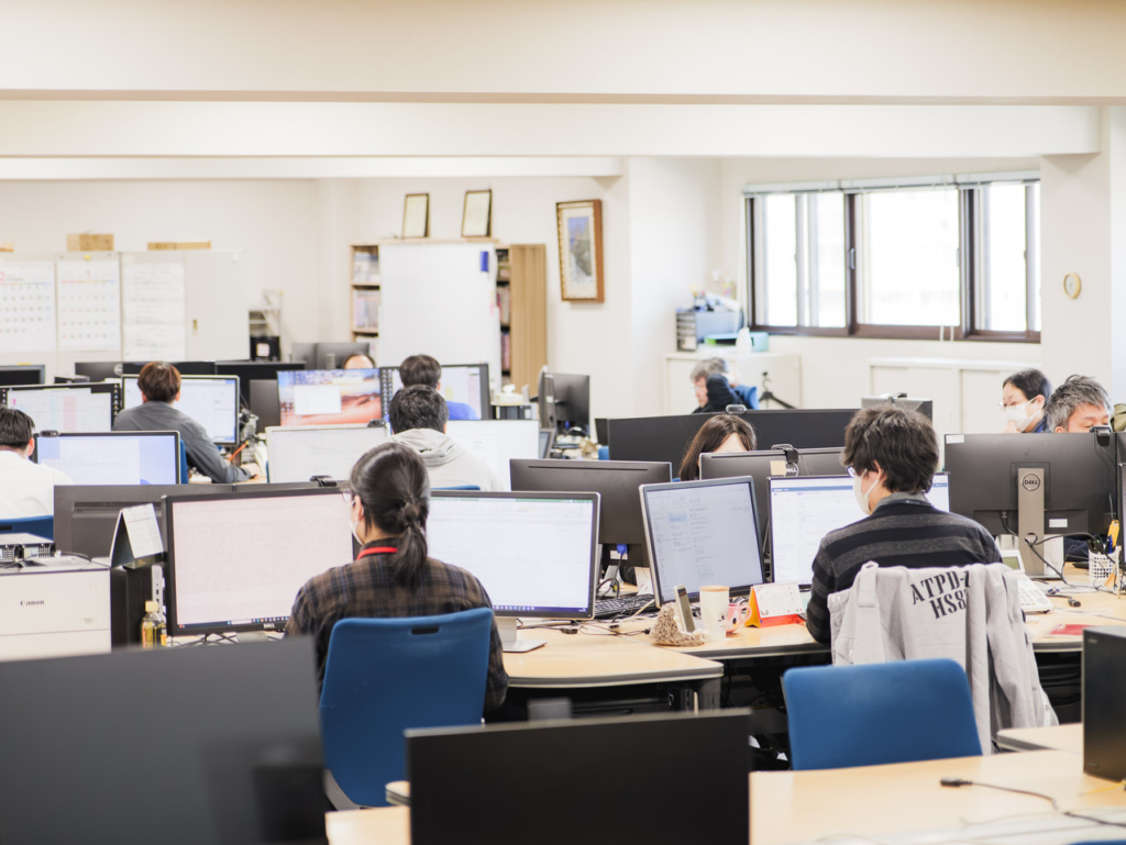 複数の社員がデスクで作業をしているオフィスフロアの全景