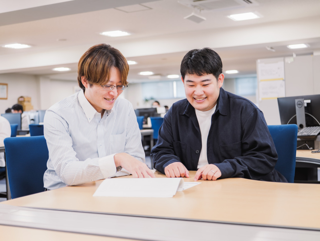 書類を見ながら業務の相談をしている2名の社員