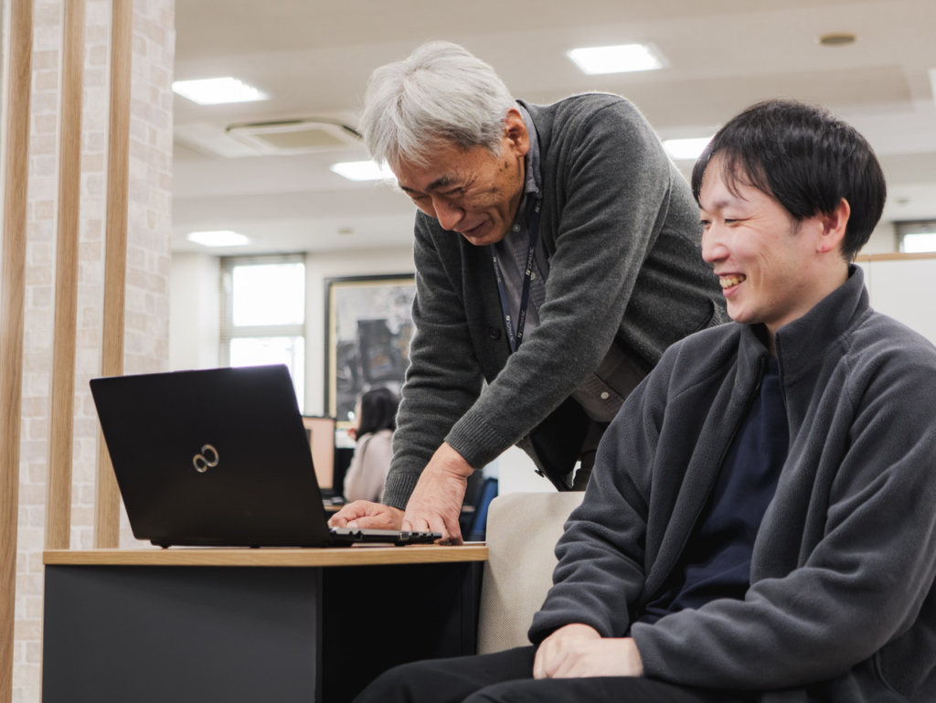 ノートパソコンを見ながら話している2名の社員