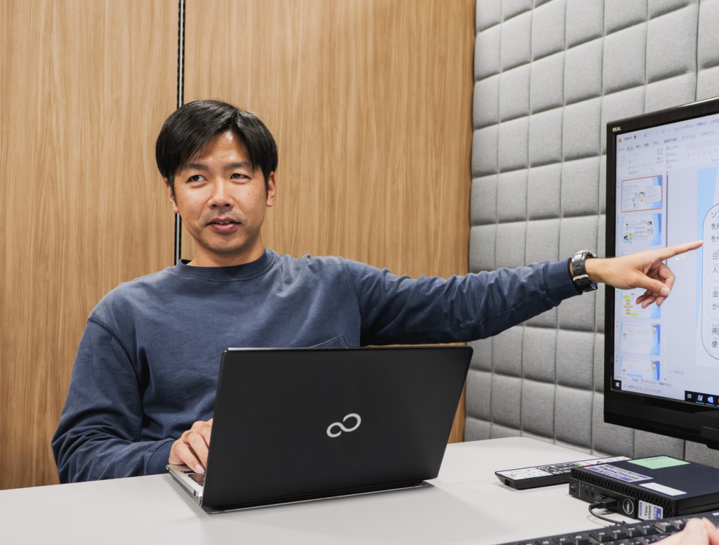 モニターを指差してプレゼンテーションを行う社員