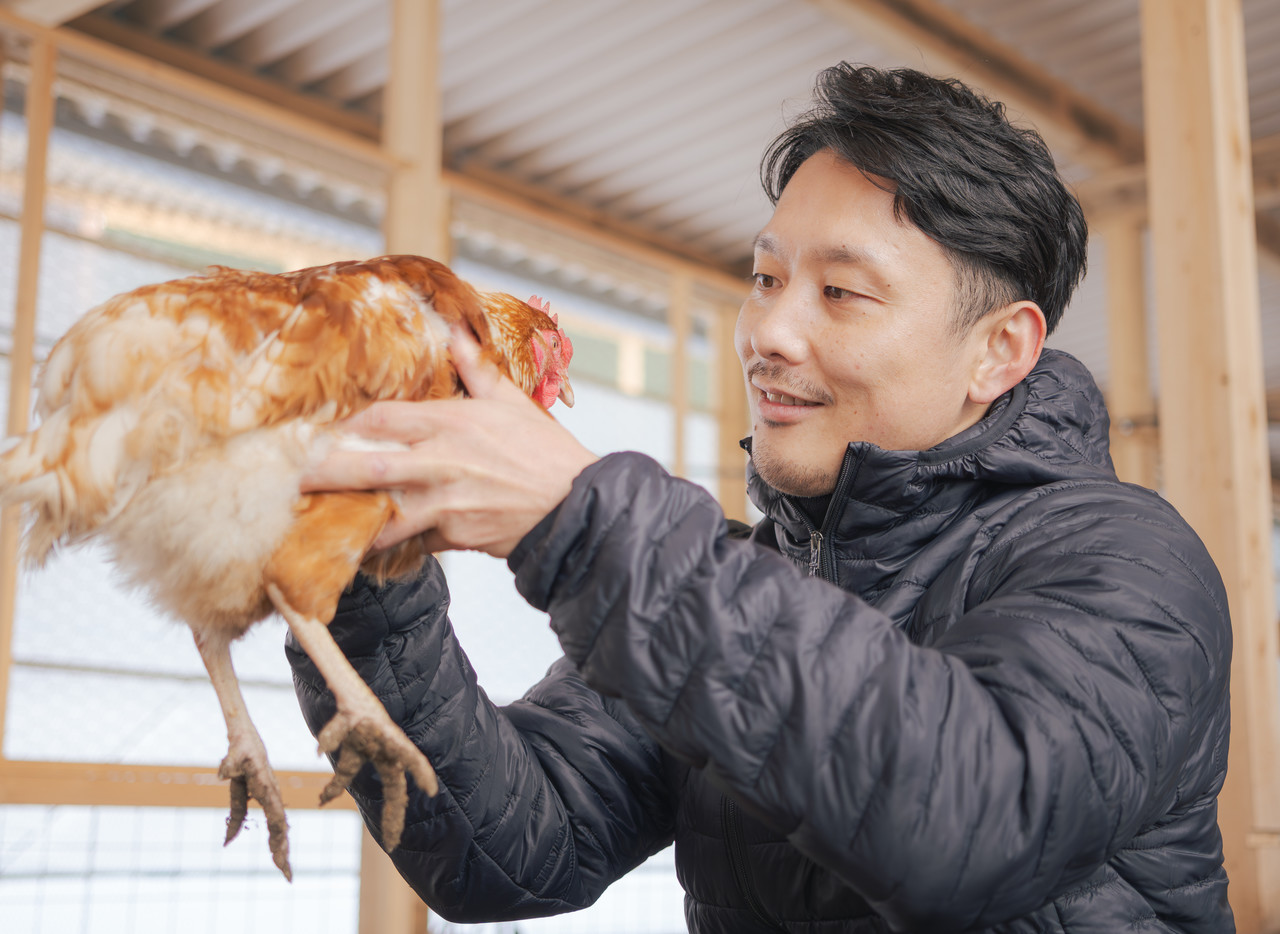 鶏を両手で持つ男性