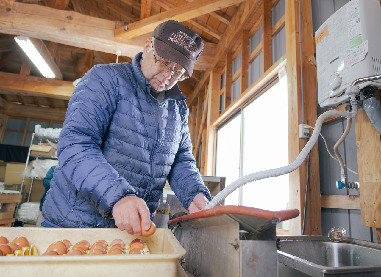 機械を使って卵を洗う男性