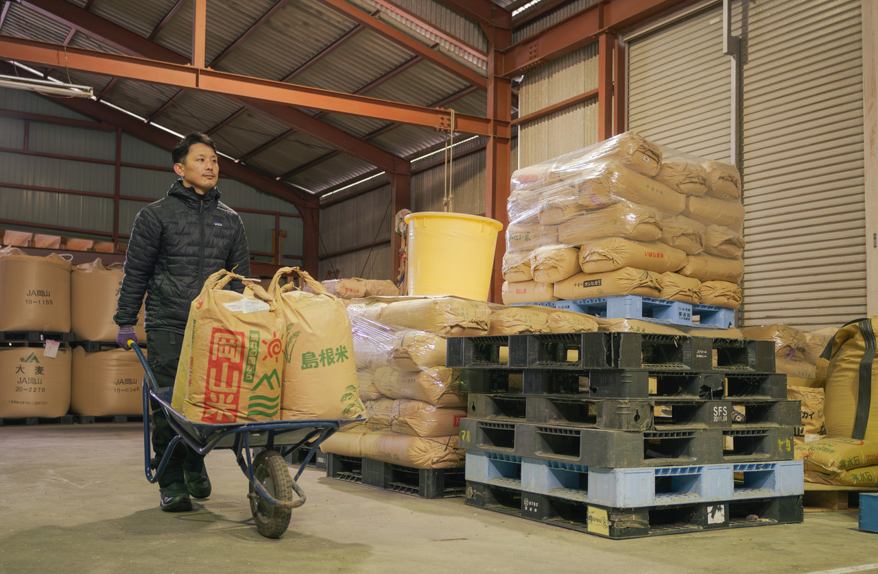 一輪車で袋を運ぶ男性