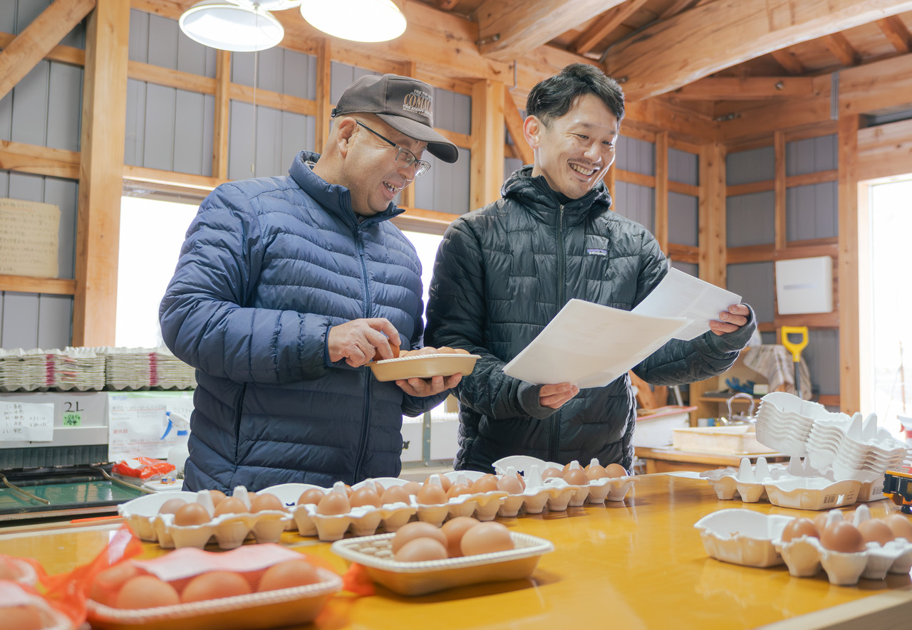 卵の梱包作業場で会話する二人の男性