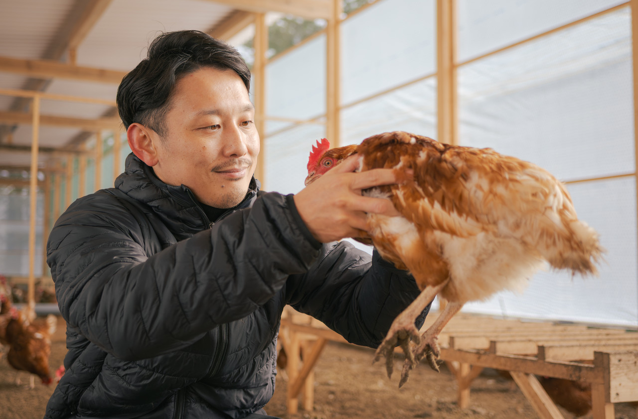 鶏を両手で持つ男性