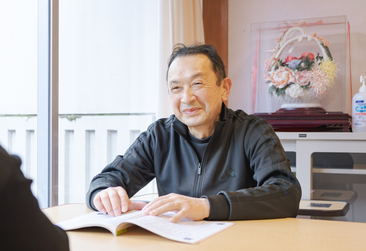 テーブル越しにスタッフと笑顔で対話する社会福祉法人加茂光陽会の施設長、河本泰精氏