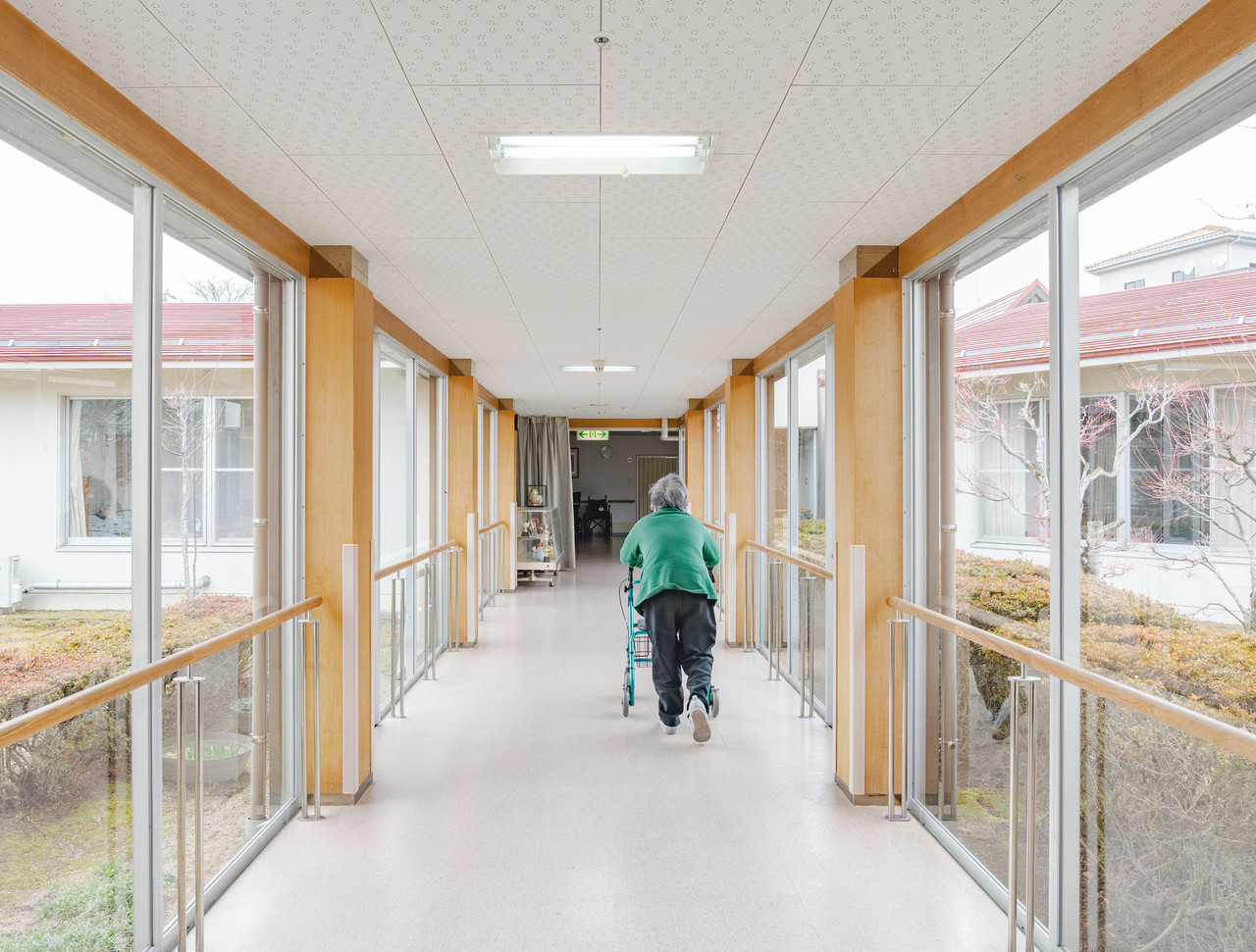 両側が大きなガラス窓になっており、中庭の緑を眺めながら歩行ができる明るい廊下。