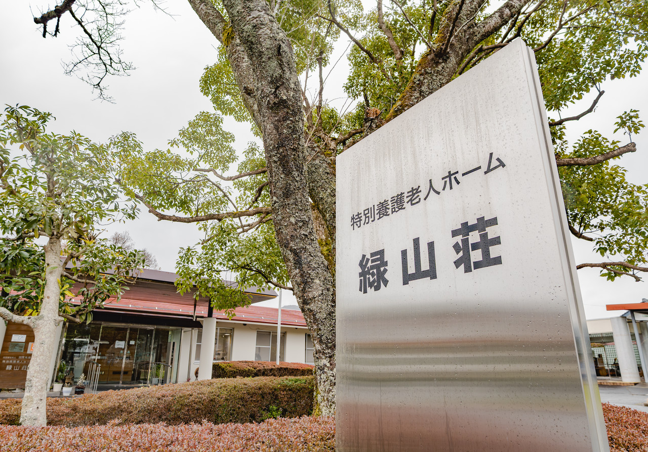 木々の間に立つ「特別養護老人ホーム 緑山荘」の看板と施設の外観