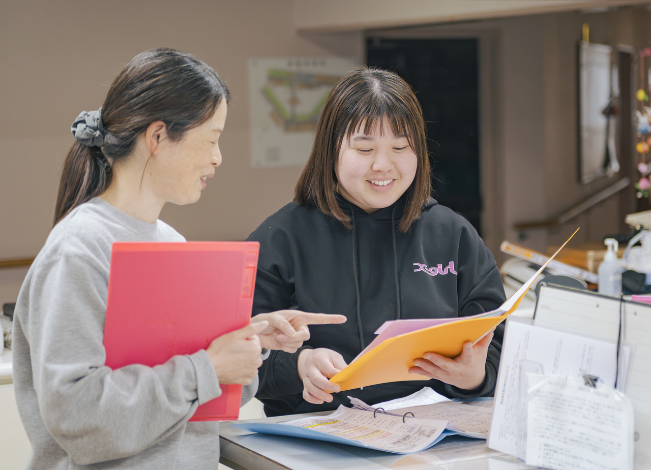 現場で先輩介護スタッフが新人スタッフに業務の手順や記録方法について教えている様子