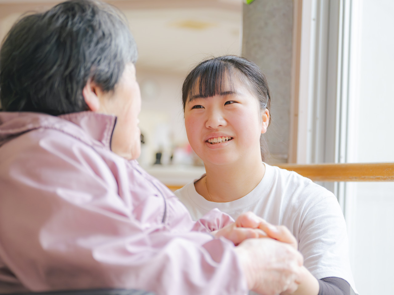 介護スタッフが高齢の利用者と笑顔でコミュニケーションをとっている様子