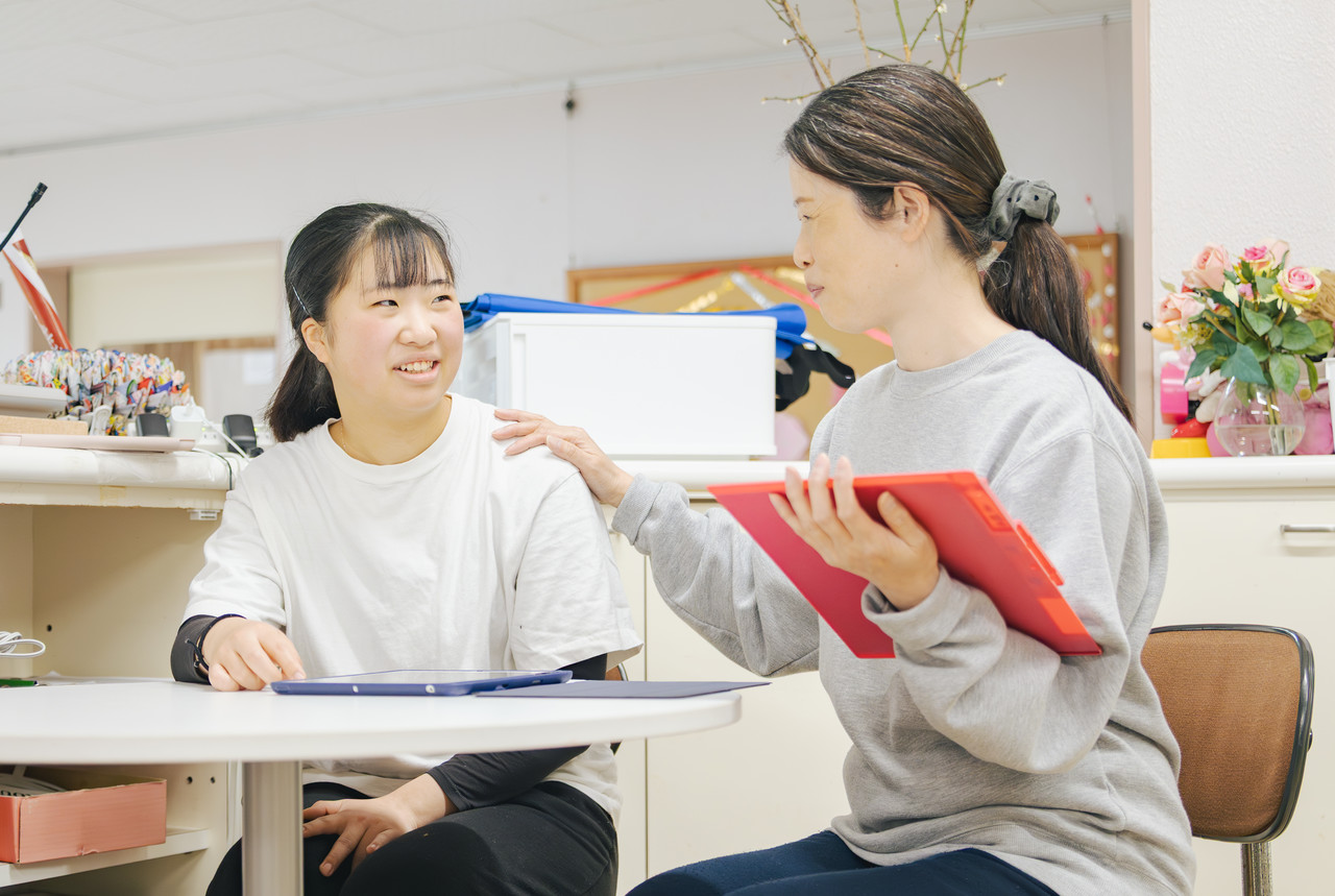職場で若いスタッフとベテランスタッフが和やかな雰囲気で会話や相談をしている様子