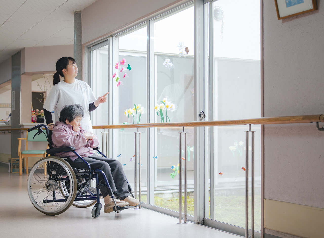 施設内で介護スタッフが利用者と一緒に散歩をしたり対話をしてゆったりと過ごす様子