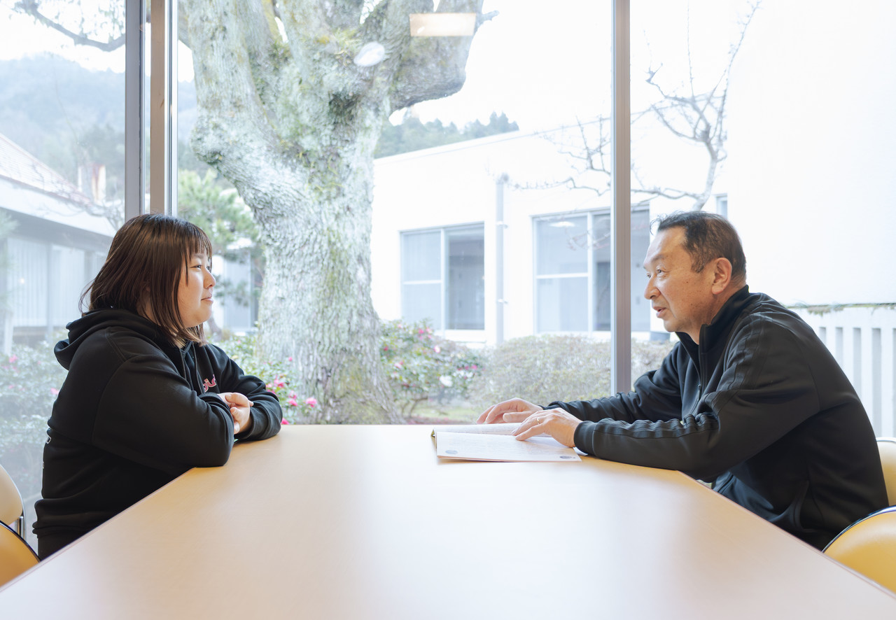 介護スタッフが上司とテーブルを囲み、日々の業務や今後の目標について面談している様子