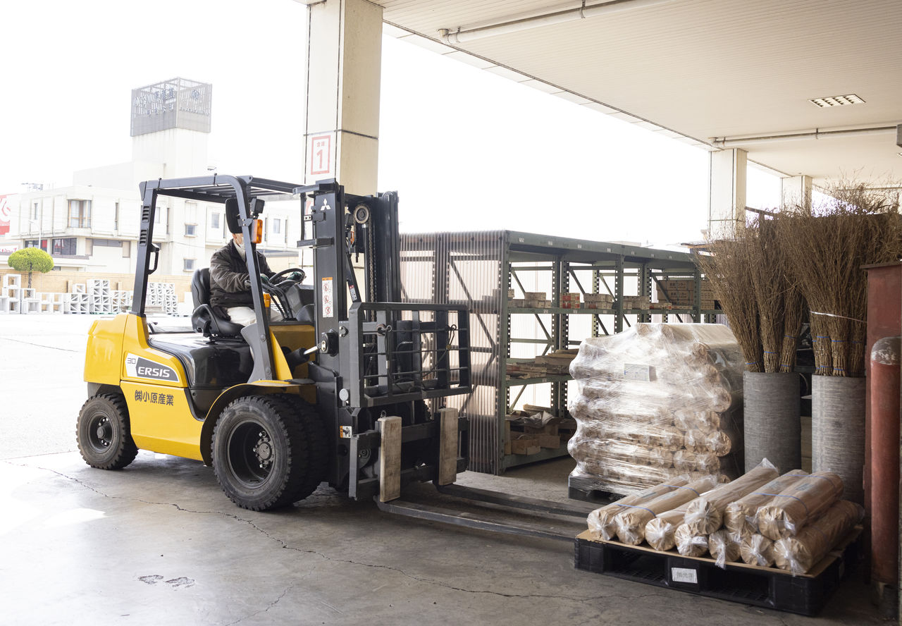 建材センターの倉庫内でフォークリフトを運転し、出荷作業を行う従業員。