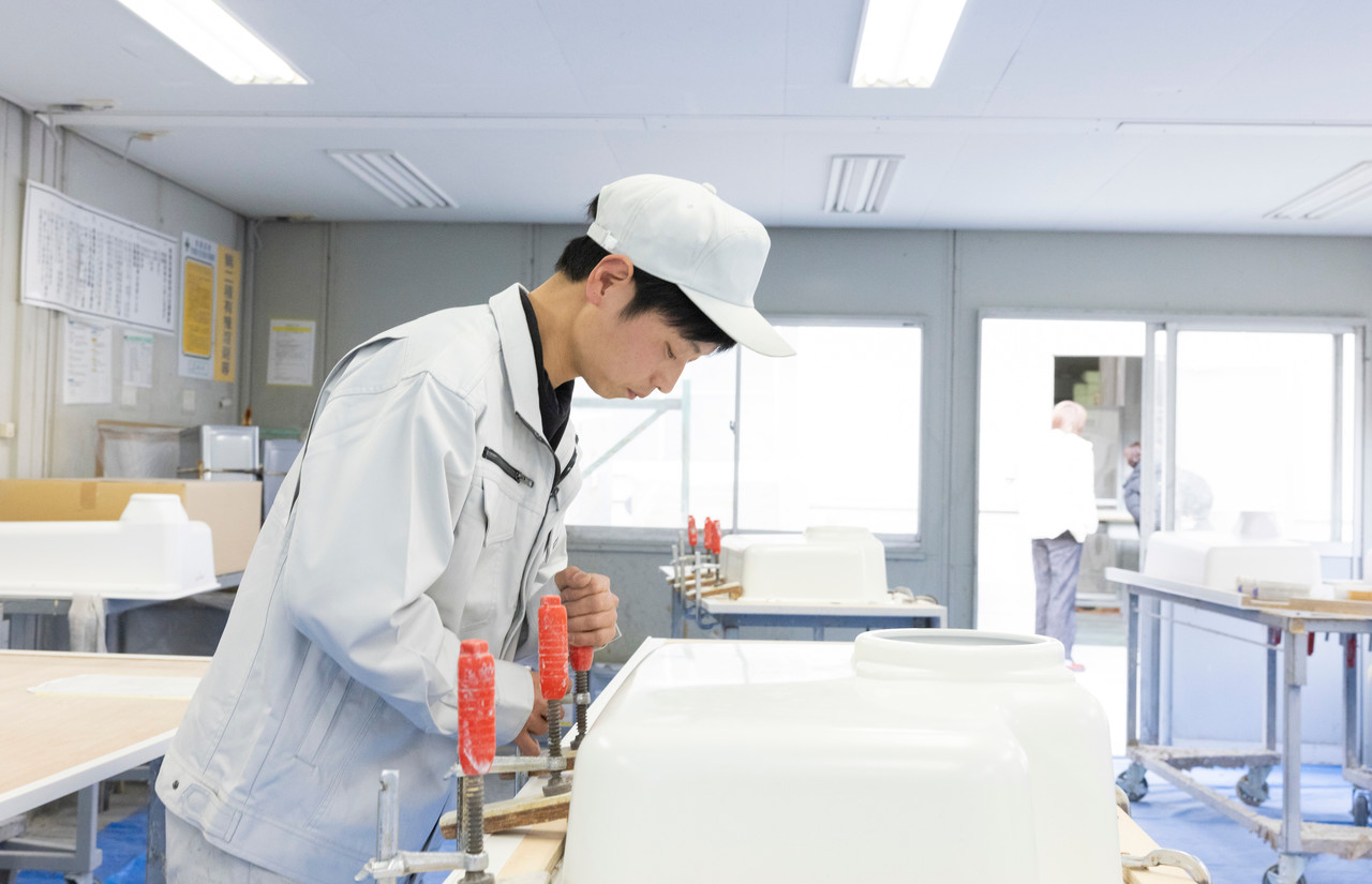 クランプで固定したカウンター材にシンクを取り付けるスタッフ