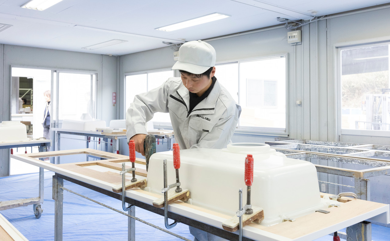 カウンター材に電動ドライバーでシンクを取り付けるスタッフ