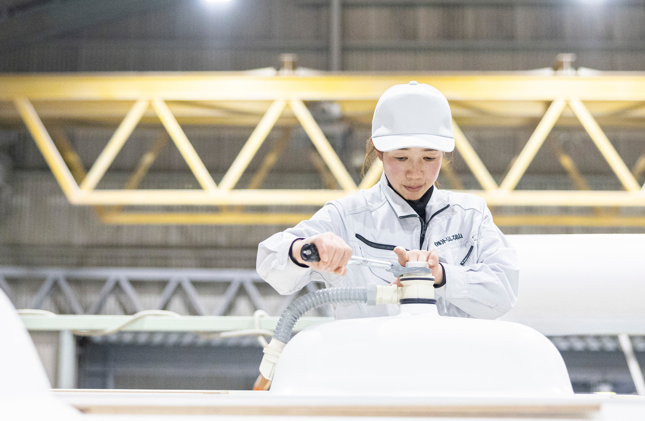 洗面ボウルの排水部品を取り付ける女性スタッフ