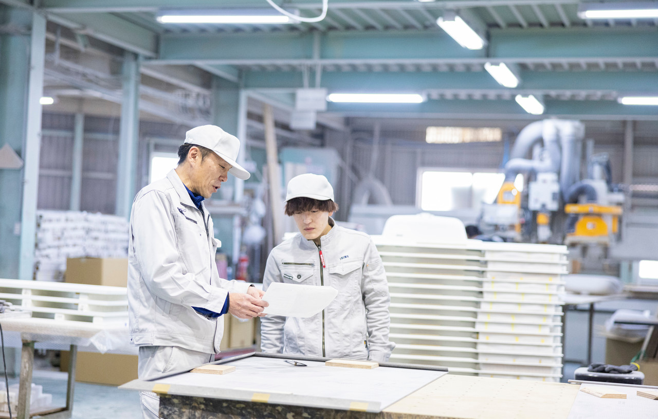 工場内で図面を確認しながら打ち合わせをするスタッフ2名