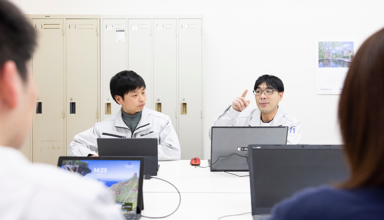 会議室で説明を行う川上さん含めた4人のスタッフ