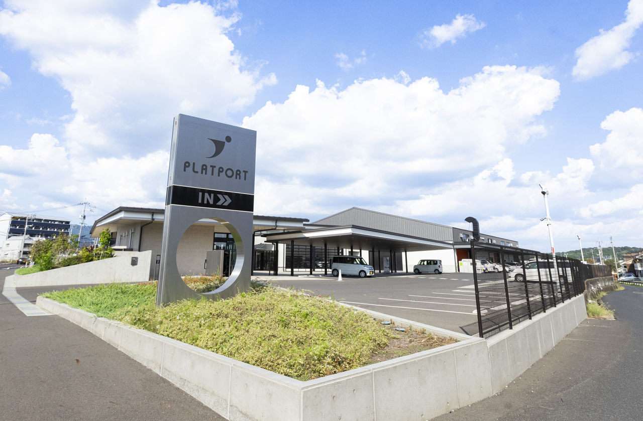 青空を背景にした、道路沿いにあるPLATPORTの看板と建物の広角写真。