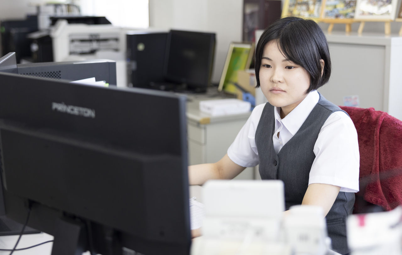 オフィスでデスクのパソコンモニターに向かって業務を行っている女性社員