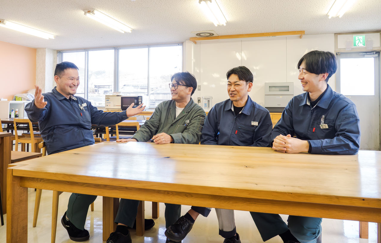 食堂のテーブルを囲み、渡邊さんを含めた4人の男性社員が笑顔で談笑している様子
